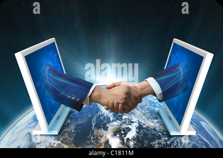 Businessmen shaking hands emerging from laptop Stock Photo