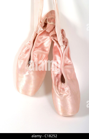 A pair of new, once worn, ballet shoes or toeshoes hanging on the wall. Stock Photo