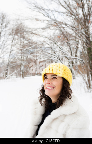 Woman with yellow cap standing in woods Stock Photo