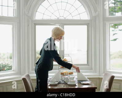 Woman setting up table Stock Photo