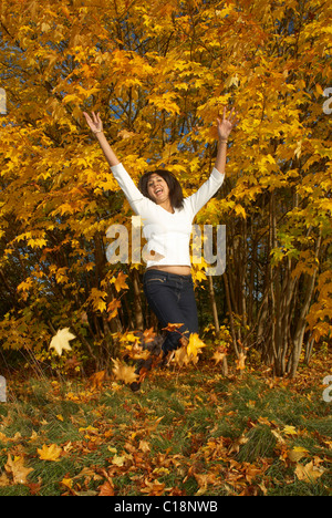Woman jumping and throwing leaves Stock Photo