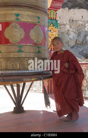 Novice monk spinning a giant prayer wheel at Spituk Gompa, near Leh, (Ladakh) Jammu & Kashmir, India Stock Photo