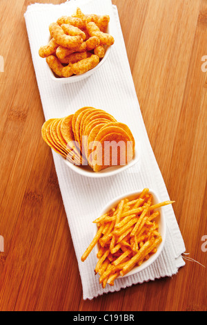 Various spiced snacks in bowls on a table, peanut flips, crisps, potato sticks Stock Photo