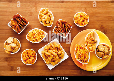 Various spiced snacks in bowls on a table, crisps, peanut flips, potato sticks, roasted peanuts, pretzel sticks and potato rings Stock Photo