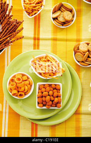 Various spiced snacks in bowls, crisps, potato sticks, roasted peanuts, pretzel sticks and potato rings Stock Photo