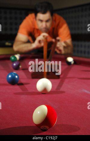 Snooker player taking a long shot across the table (focus on the first ball) Stock Photo