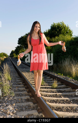 Young woman, nineteen years old, balancing barefoot on a rail Stock Photo