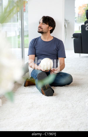 Man sitting on the floor beaming, holding a glass ball in his hands Stock Photo