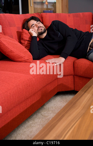 Man lying on a sofa, sleeping Stock Photo