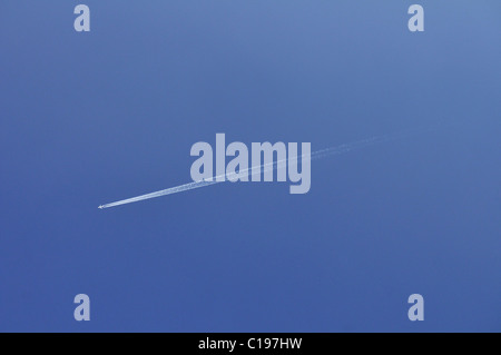 Airplane with vapour trail in blue sky Stock Photo
