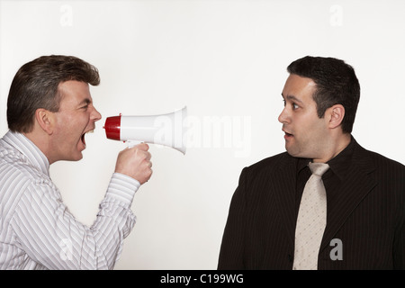Businessman yelling orders to his colleague through a megaphone Stock Photo