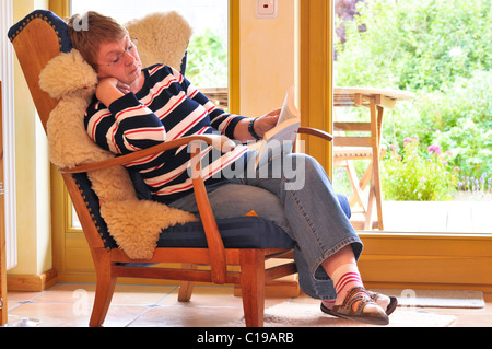 Woman sitting in a comfortable chair and reading a book Stock Photo