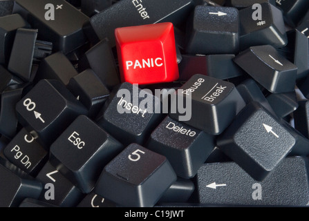 A pile of black computer keyboard keys with bright red PANIC button on the top of the stack Stock Photo