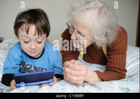 6 year old playing on his nintendo DSi and showing his grandma Stock Photo