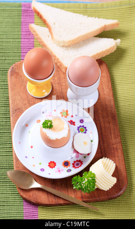 Three boiled eggs in porcelain eggcups and white bread Stock Photo