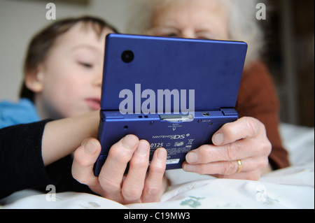 6 year old playing on his nintendo DSi and showing his grandma Stock Photo