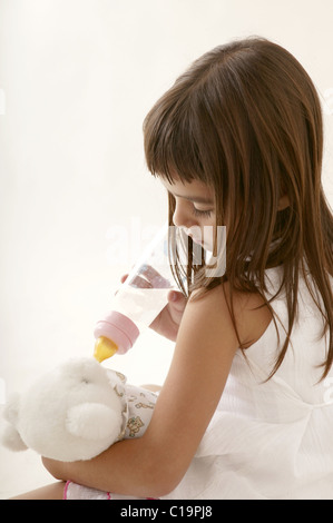 beautiful little latin girl feeding her teddy bear Stock Photo