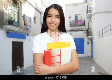 Brunette student young girl teen latin holding books white mediterranean village Stock Photo