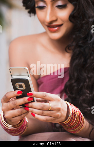 Bride in traditional Bengali dress text messaging on a mobile phone Stock Photo