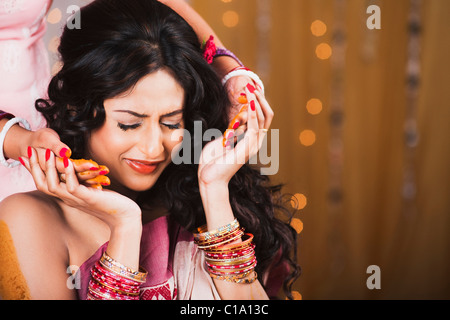 Bride's friends and family apply turmeric paste to her body as a part of Gaye Holud ceremony in Bengali Wedding Stock Photo