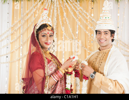 Couple performing Mala Badal (Garland Exchanging) ceremony in Bengali wedding Stock Photo