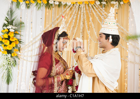 Couple performing Mala Badal (Garland Exchanging) ceremony in Bengali wedding Stock Photo