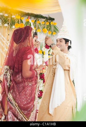 Couple performing Mala Badal (Garland Exchanging) ceremony in Bengali wedding Stock Photo