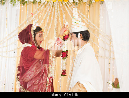 Couple performing Mala Badal (Garland Exchanging) ceremony in Bengali wedding Stock Photo