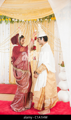 Couple performing Mala Badal (Garland Exchanging) ceremony in Bengali wedding Stock Photo