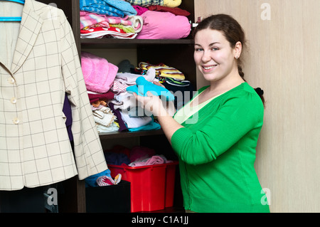 Young Caucasian woman in the wardrobe packs things on a shelfs. Stock Photo