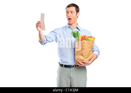 Shocked man looking at store receipt and holding a grocery bag Stock Photo