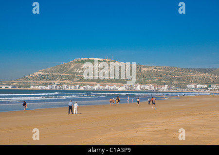 People walking on beach with Kasbah in background Agadir the Souss southern Morocco Africa Stock Photo