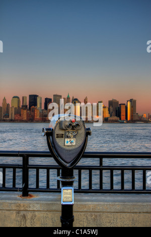 Commercial binoculars aimed at lower Manhattan across the Hudson River at sunset from Liberty State Park in New Jersey Stock Photo