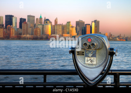 Commercial binoculars aimed at lower Manhattan across the Hudson River at sunset from Liberty State Park in New Jersey Stock Photo