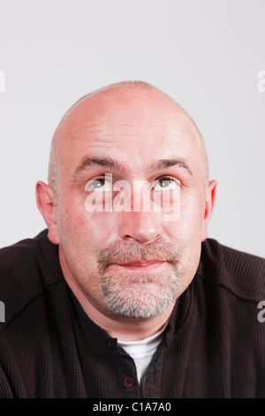 Mature man looking upwards and thinking with a faraway facial expression and raised eyebrows. UK, Britain Stock Photo