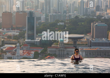 Woman swimming in pool at Marina Bay Sands SkyPark with city skyline in background.  Marina Bay, Singapore Stock Photo