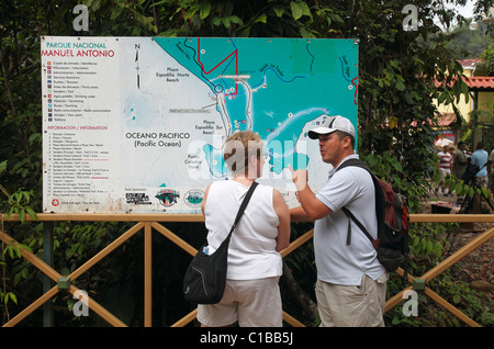 A guide talks with a tourist in front of a map at the entrance to Manuel Antonio National Park, Costa Rica Stock Photo