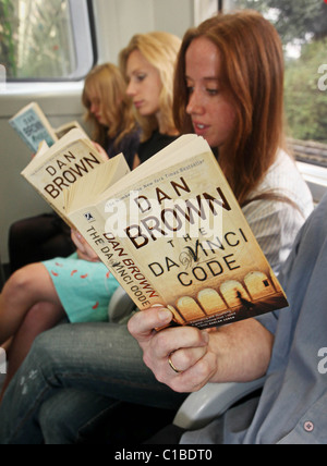 Commuters (posed) reading a selection of Dan Brown books on the London underground train -12th of August 2009. Stock Photo