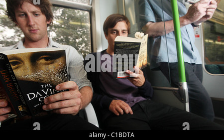 Commuters (posed) reading a selection of Dan Brown books on the London underground train -12th of August 2009. Stock Photo