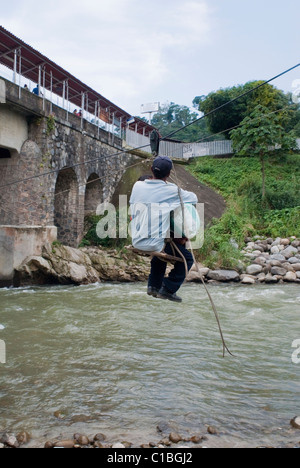 A primitive zip line with a wooden seat serves to move people and merchandise from Guatemala to Mexico over the Suchiate River. Stock Photo