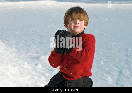 Cute ginger haired boy ready to throw a snow ball on a winter day Stock Photo