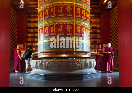 Monks and giant prayer wheel in the 10,000 Buddha Pavilion.  Buddha Tooth Relic Temple and Museum, Chinatown, Singapore Stock Photo