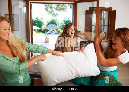 Women having pillow fight on hotel bed Stock Photo