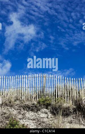 Wooden picket fence on sand dune with blue sky Stock Photo