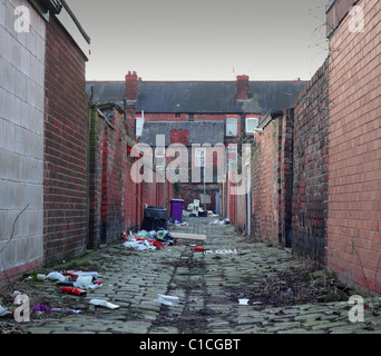 Household rubbish left lying about in a dirty back street cobble stoned  alley Stock Photo
