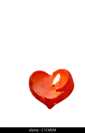 Red heart-shaped candle burning on a white background