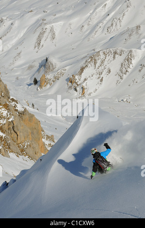 A snowboarder carves a turn in deep powder snow off piste in the Les Avals area of the Courchevel ski resort in the French Alps. Stock Photo