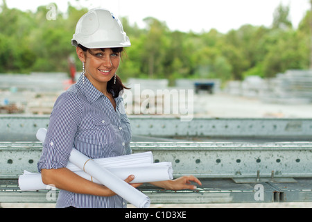 Young engineer woman standing with rolled drawings in the warehouse Stock Photo