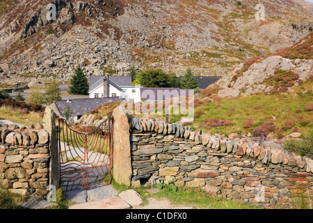 Ogwen Valley, Snowdonia, North Wales, UK. Footpath from Cwm Idwal with Ogwen Cottage Outdoor Pursuits Centre beyond drystone wall Stock Photo