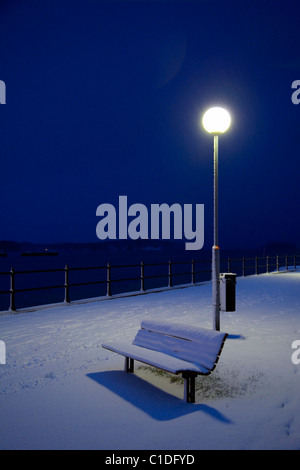 Park bench covered in snow at night Stock Photo